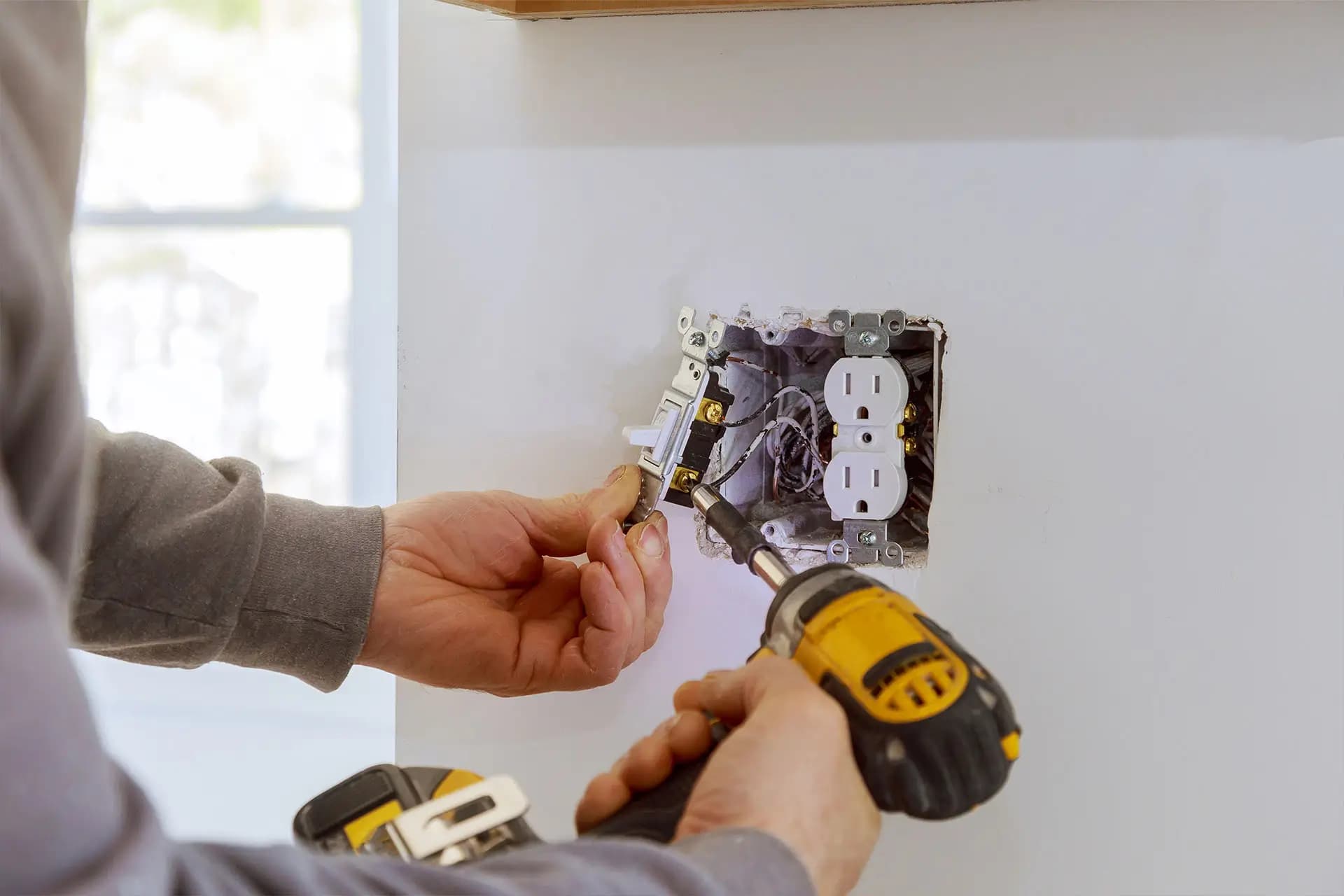 Setting a switch and a receptacle into a wall box with a cordless drill