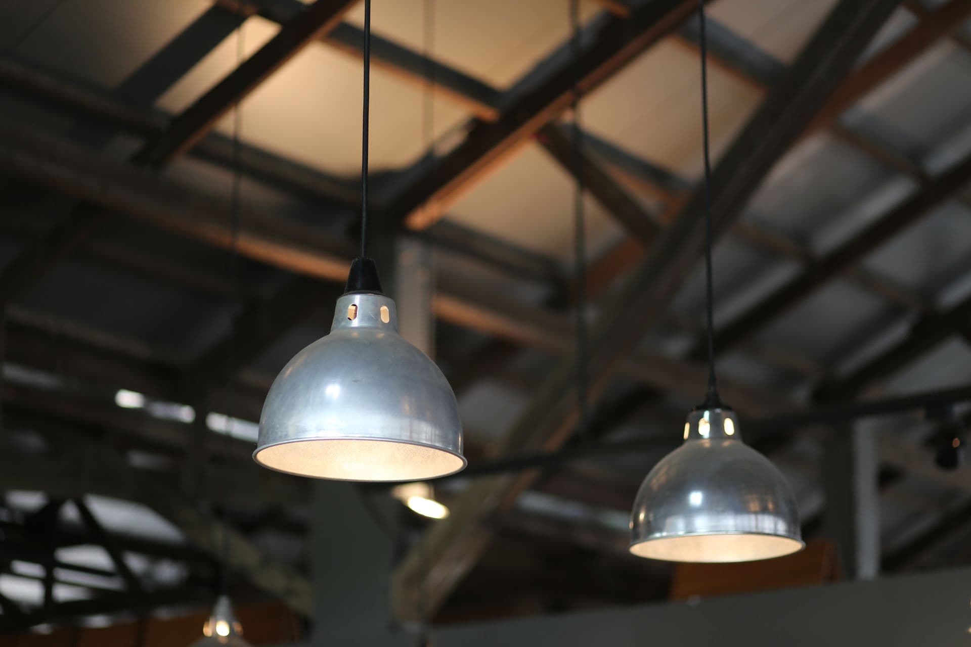 Industrial pendant high-bay lamps lit beneath an exposed warehouse roof structure