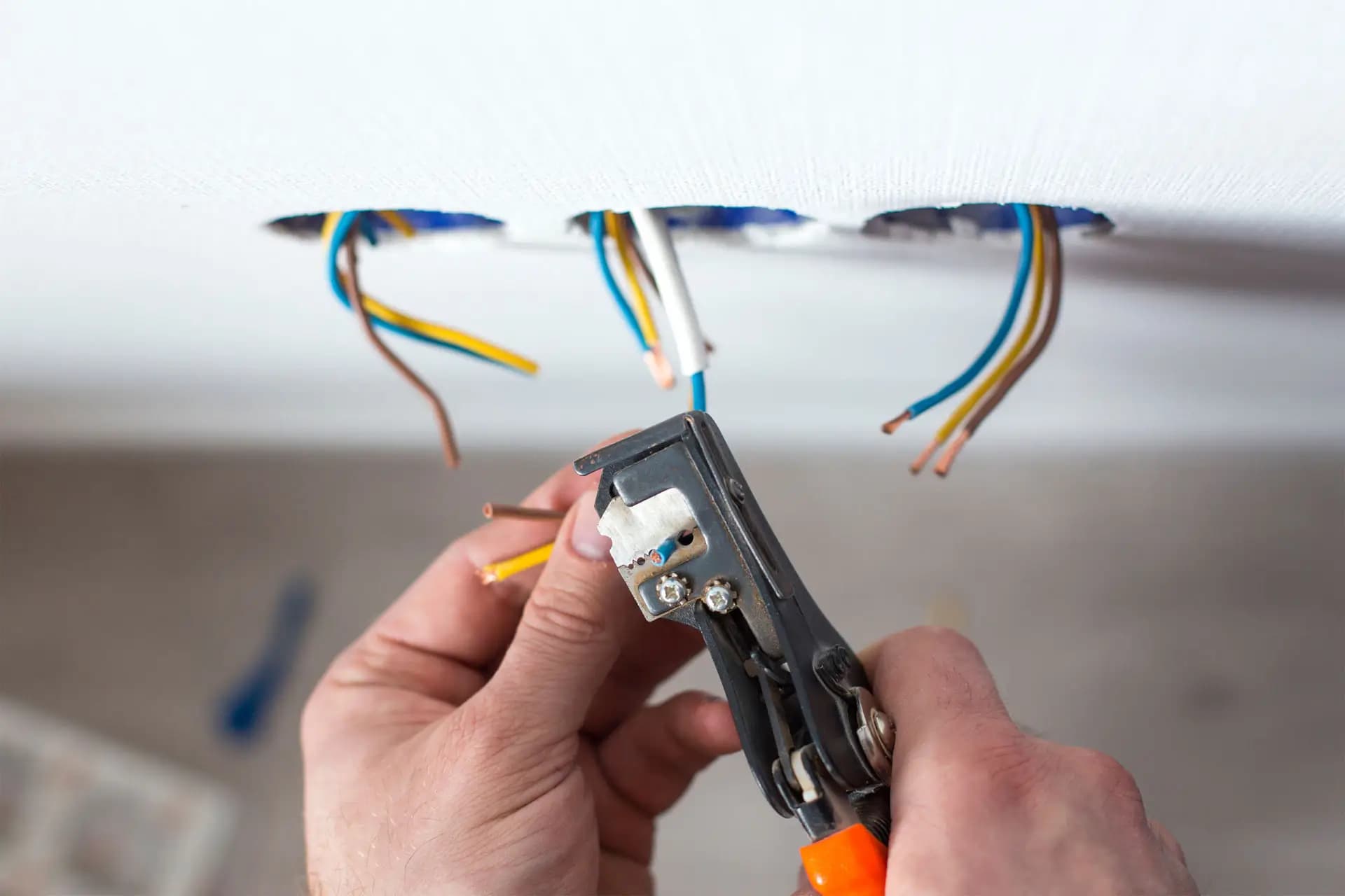 Stripping insulation from a conductor below a ceiling where cables hang out of cut-in openings